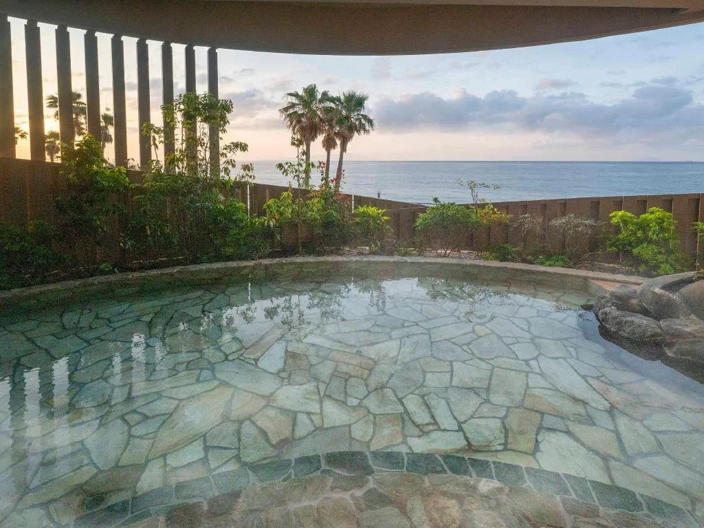 Stone-lined outdoor bath looking toward the sea at Atagawa Ocean Resort